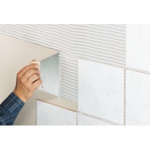 LUX Zahnspachtel Classic 6x6 mm beim Auftragen von Fliesenkleber auf eine Wand.