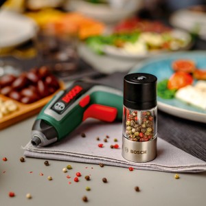 Bosch Akkuschrauber IXO 7 Set mit Gewürzmühle als Aufsatz auf gedecktem Tisch.