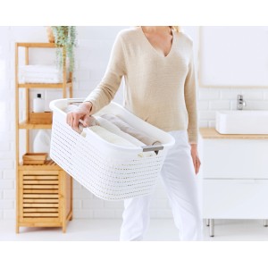 Donna che trasporta cesto portabiancheria Rotho Country bianco (40 l) con struttura in rattan in bagno.