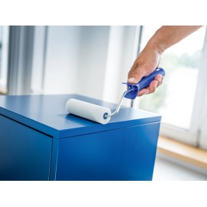 Rouleau en mousse LUX (11 cm, blanc, 5 pièces) en train de peindre une surface bleue.