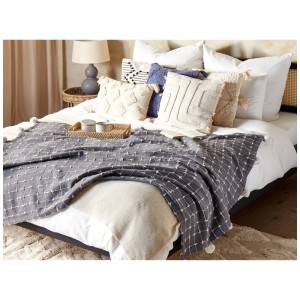 Coperta grigia Beliani Yasam in cotone (125x150 cm) con motivo a quadri e nappe su un letto.