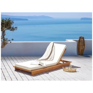 Lettino prendisole Beliani Granari in legno acacia marrone con cuscino bianco, vista mare.