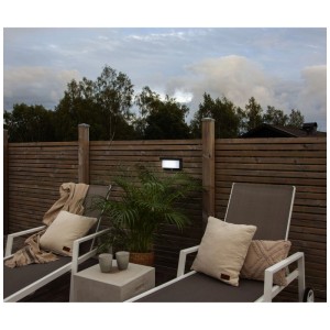 Applique murale solaire noire Star Trading Valla sur un mur en bois au-dessus de meubles de jardin.