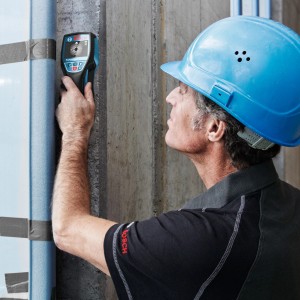 Artisan utilisant un détecteur Bosch Professional D-tect 120 sur un mur pour la détection de câbles.