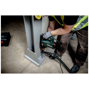 Arbeiter bohrt mit grünem Metabo Kombihammer KHE 3560 Q in Metallträger, Staubabsaugung aktiv.