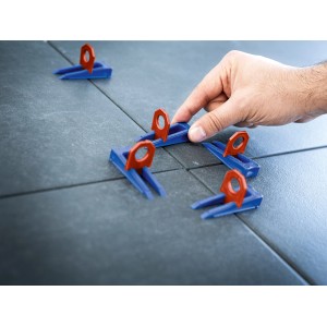 Set di livellamento LUX con cunei e clip (2 mm) in uso tra le piastrelle.