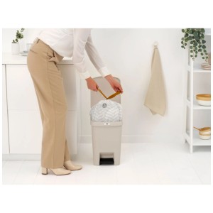 Donna che cambia il sacco della spazzatura nel cestino a pedale Brabantia Step-up beige 25L.