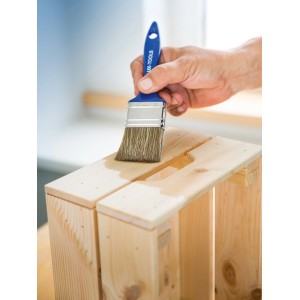 Mano che vernicia una cassa di legno con pennello piatto LUX 30mm. Pennello con manico blu.