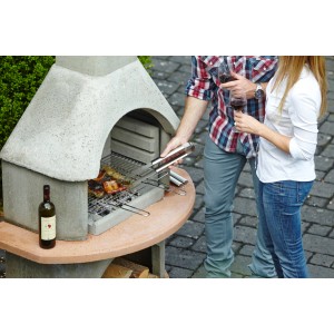 Cheminée barbecue Buschbeck Carmen gris-terre cuite avec couple grillant dans le jardin.