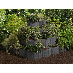 Anneaux de plantation anthracite, plantés de fleurs et de lierre, empilés comme soutènement de pente.