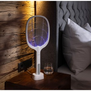 Tapette à mouches électrique 2-en-1 Windhager avec lumière UV sur sa station de charge, posée sur une table de chevet.