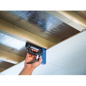 Cucitrice manuale LUX che fissa materiale isolante a un soffitto.
