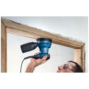 Ponceuse excentrique Bosch Professional GEX 125 en action sur un cadre de fenêtre.