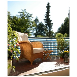 Balcon avec brise-vue Classic bleu et blanc, fauteuil en osier et petite table.