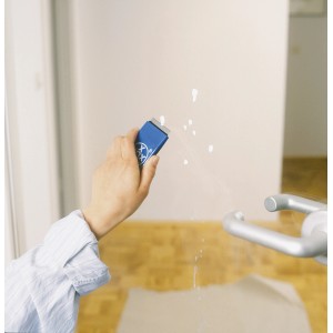 Main utilisant un grattoir universel LUX avec lame pour enlever des éclaboussures de peinture sur du verre.