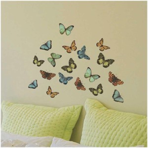 Sticker mural "Colorful Butterflies" (taille S) sur un mur au-dessus d'un lit.