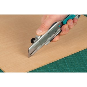 Coltello professionale a lama spezzabile Wolfcraft 25 mm taglia legno su tappetino verde.