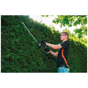 Taille-haie sans fil Batavia 18 V en utilisation : homme taillant une haie. Taille-haie sans fil pour l'entretien du jardin.