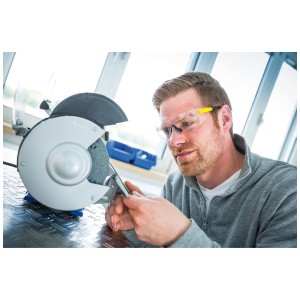 Homme portant des lunettes de protection transparentes LUX 200 pendant le meulage. Protection oculaire avec revêtement antibuée.