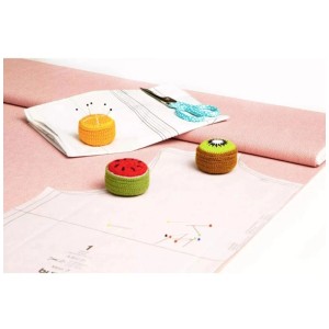 Cuscino per aghi a forma di melone Prym e altri design di frutta come pesi di fissaggio sul tavolo da cucito.