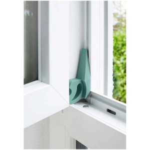 Fermaporta Wenko Multi-STOP® color menta in plastica fissato al telaio della finestra.
