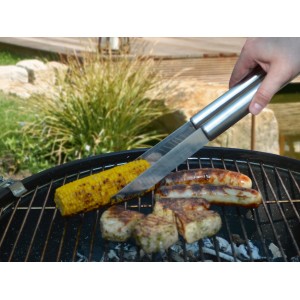Pinces en inox en utilisation : maïs, saucisses et viande en grillade. Set d'ustensiles pour barbecue.