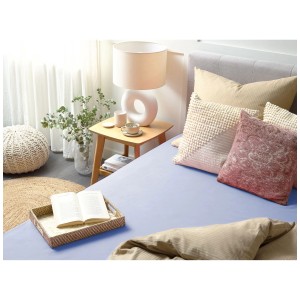 Lenzuolo con angoli Janbu in cotone blu 140x200 cm su un letto con cuscini e comodino.