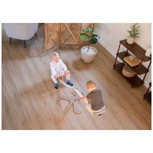 Deux enfants jouent sur la balançoire Exit Toys My First en acier aux couleurs pastel à l'intérieur.