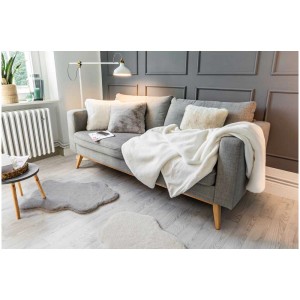 Coperta Coste bianca (130x180 cm) su divano grigio in soggiorno.