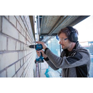 Avvitatore a percussione Bosch Professional GSB 18V-45 durante la foratura in muratura.