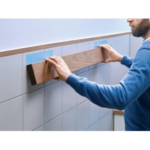 Uomo fissa listello di legno a parete piastrellata con nastro di montaggio Tesa. Tenuta forte per applicazioni permanenti.