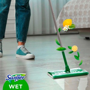 Balai Swiffer avec lingette humide en utilisation, citron et feuilles flottant dans l'air.