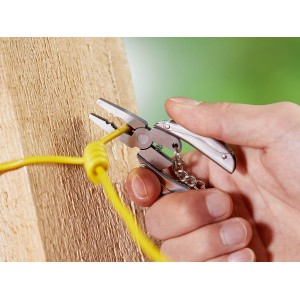 Main utilisant une pince multifonction LUX avec porte-clés pour couper un câble jaune.
