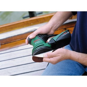 Ponceuse excentrique Bosch PEX 220 A en action avec du papier abrasif sur une surface en bois.