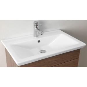 Vasque en céramique blanche brillante 65x40cm avec robinet sur meuble en bois.