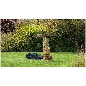 Robot tondeuse Bosch Indego S+ 500 4G sur pelouse à côté d'un abreuvoir pour oiseaux.