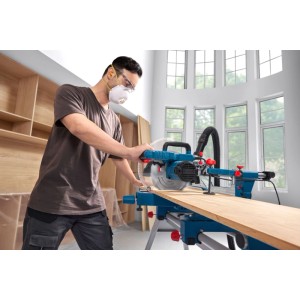 Uomo con occhiali di sicurezza usa sega troncatrice Bosch Professional. Lavorazione precisa del legno in officina.