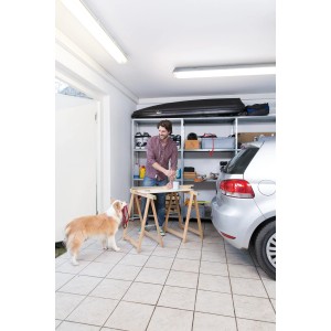 Uomo lavora in garage sotto la lampada stagna a LED Osram. Illuminazione brillante e senza riflessi.