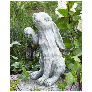 Graue Kaninchen Gartenfigur aus Magnesiumoxid mit Laterne, sitzt zwischen Pflanzen. Ideal für Gartendekoration.