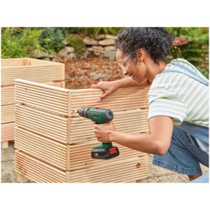 Donna che utilizza il trapano avvitatore a percussione a batteria Bosch Easy Impact 18V-40 su una scatola di legno.