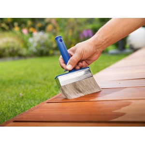 Pennello piatto LUX da 70 mm che applica la vernice su una terrazza in legno.