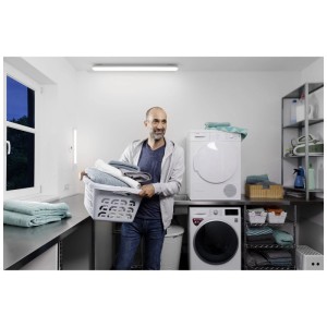 Homme avec panier à linge sous le luminaire LED étanche Ledvance dans une buanderie.