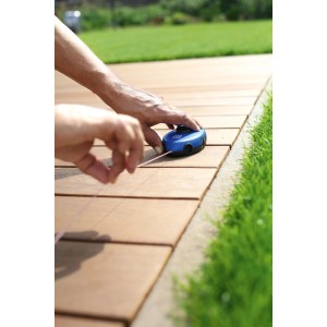 Rotella traccialinee LUX Classic 30m mentre segna una linea su pavimentazione.