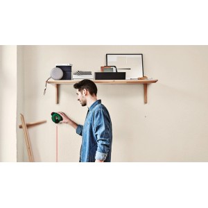 Un homme utilise un laser à ligne Bosch Atino avec un mètre ruban pour l'alignement sur un mur.