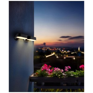 Mattschwarzer Globo LED Solar-Bodenstrahler an einer Wand montiert, beleuchtet eine Blumenbank.