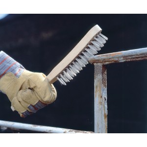 Main utilisant une brosse métallique LUX (4 rangs, inoxydable) pour enlever la rouille du métal.