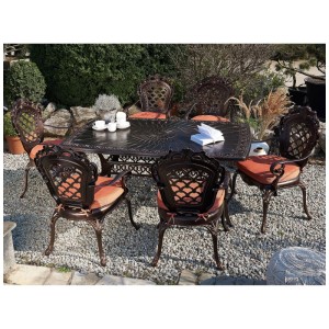 Salon de jardin Beliani Lizzano: table en aluminium marron, 6 chaises avec coussins orange, design rétro sur gravier.