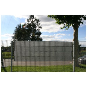 Strisce frangivista in polyrattan argento-antracite intrecciate in una recinzione a doppia maglia.