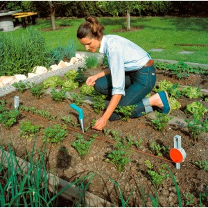 Donna che usa il piantatore Gardena nell'aiuola per piantare piantine.