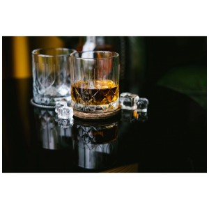 Set di bicchieri La Rochere Chicago, 4 bicchieri da whisky con cubetti di ghiaccio su tavolo nero.